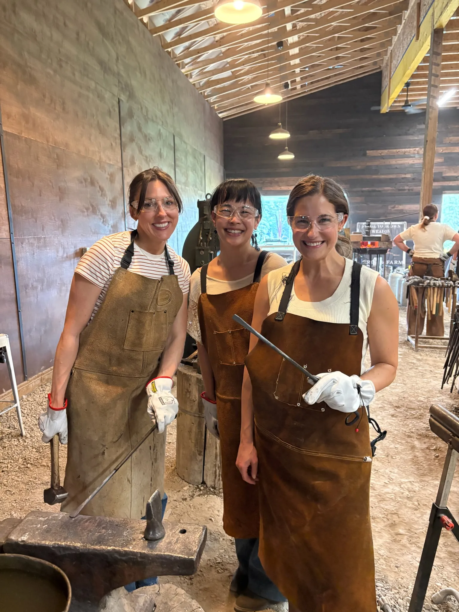 Three guests dressed in leather aprons at the forge