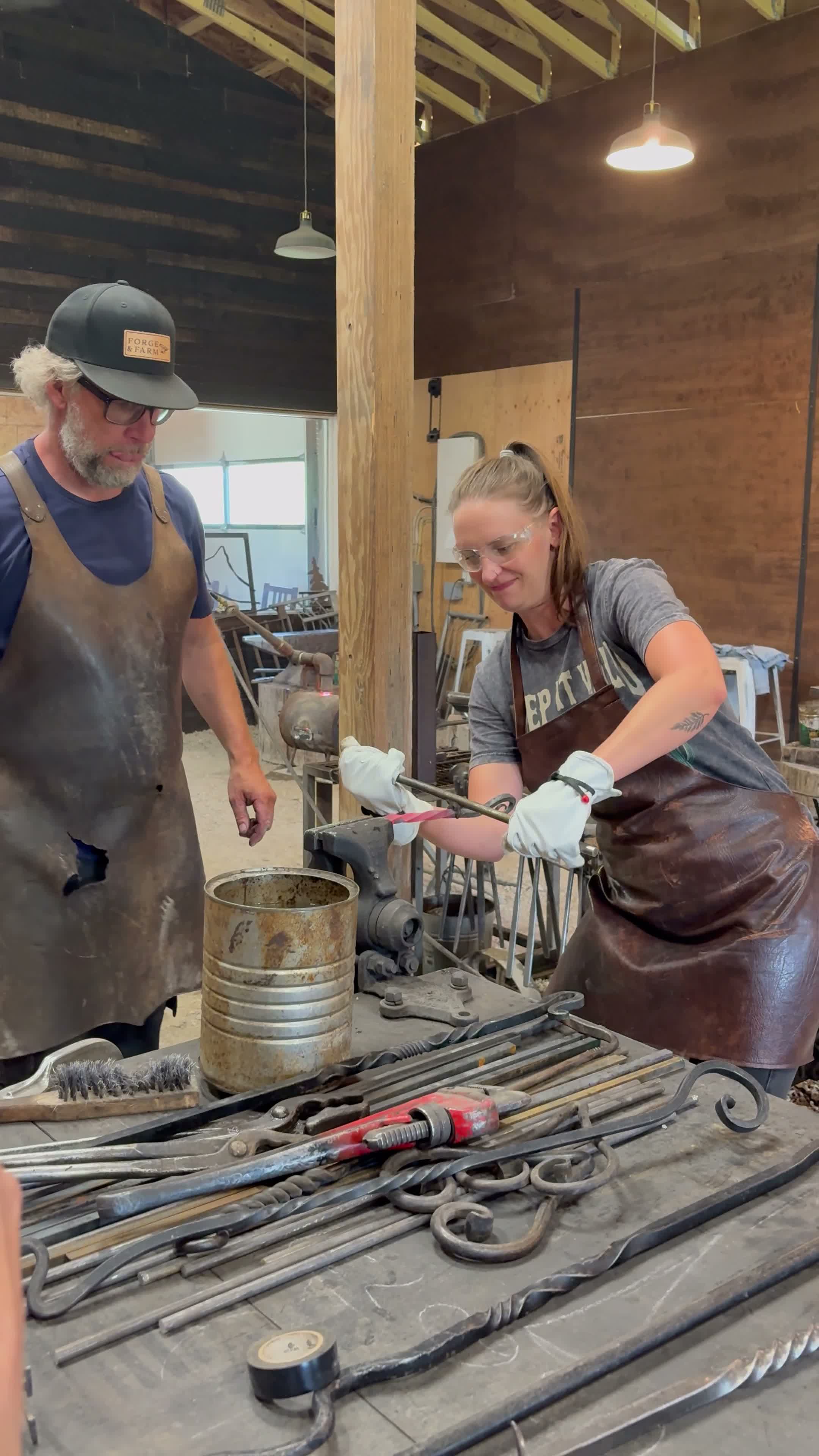 A guest shaping a glowing piece of steel with guidance from the blacksmith