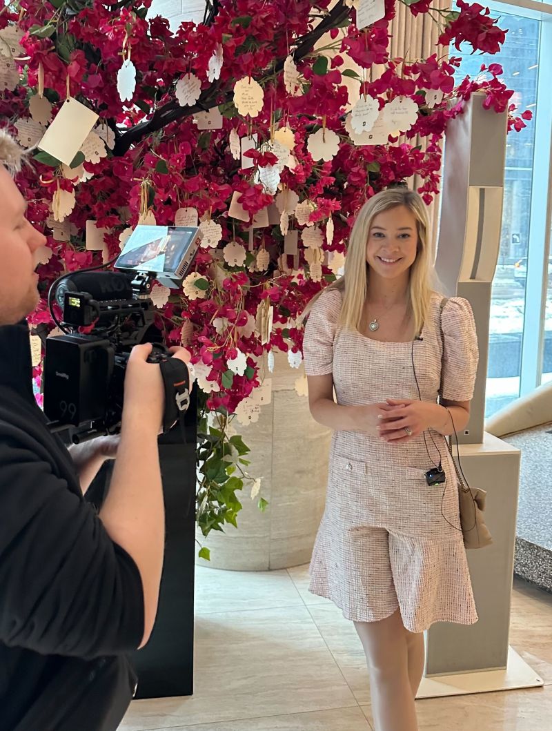 A guest being interviewed in front of the floral installation